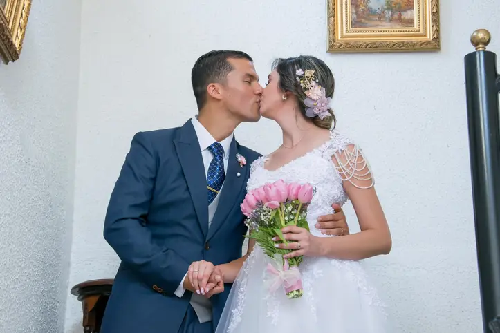 Pareja de novios besándose al pie de la escalera y preparándose para la recepción matrimonial, foto parte de nuestro servicio